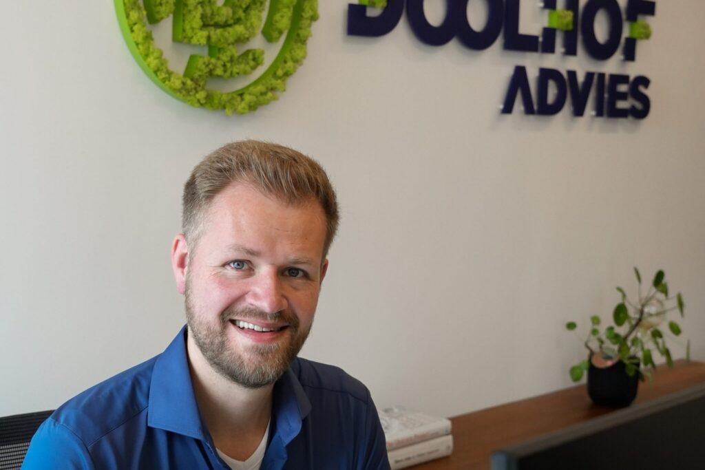 Gert Dollen bij de logowand van Doolhof Advies